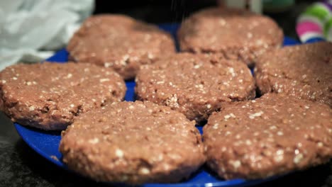 seasoning plant based burger patties on a blue plate for a summertime barbecue cookout, in 60 frames per second 4k