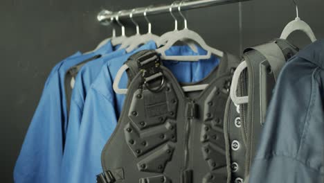 a figure removes a body armour vest from a clothes rack