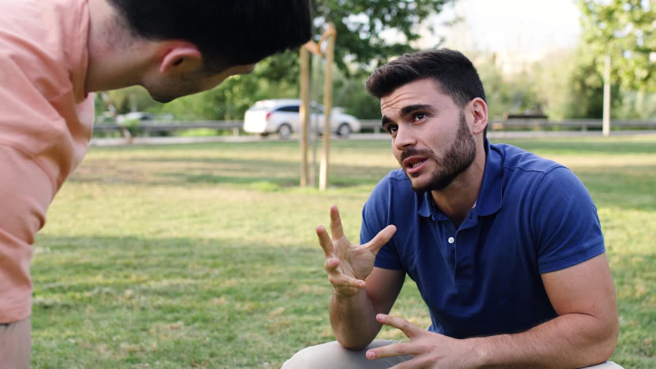 Due giovani che conversano animatamente in un parco