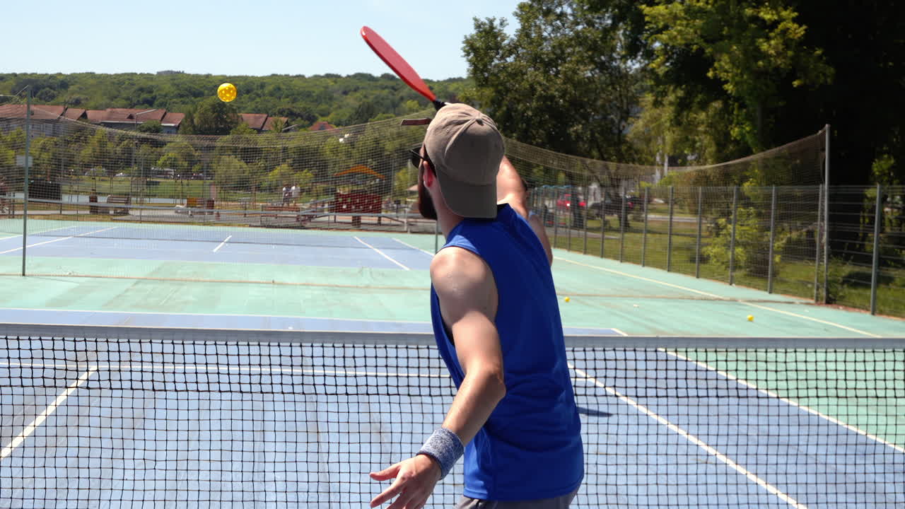 A man and a woman playing pickleball on a sunny day