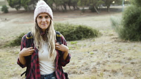 feliz chica de camping con sombrero de lana posando en el campo