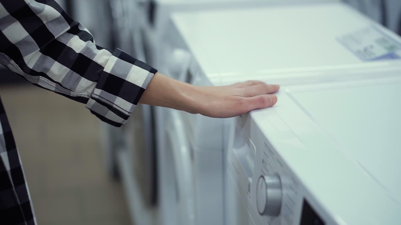 Choosing washing mashine in appliance store. Running hand by the row. Unrecognizable woman in household appliances department. Close up