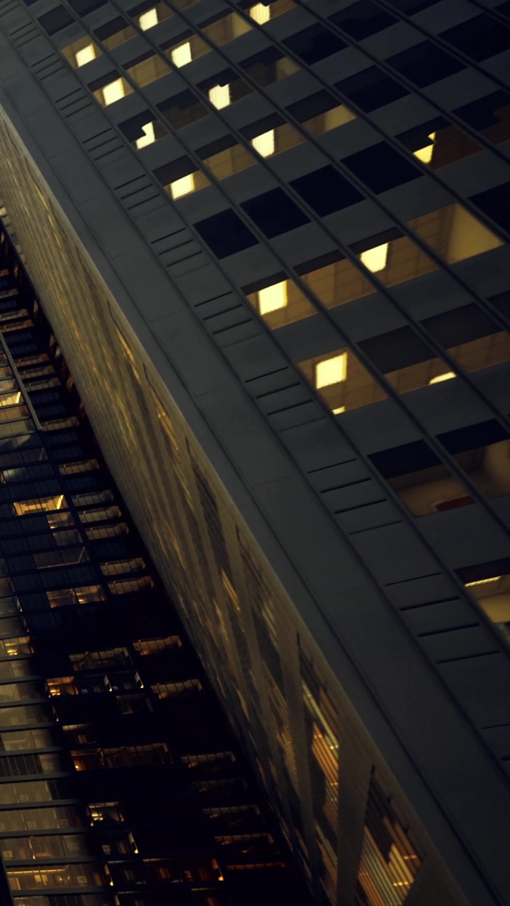 Lights from windows on a tall building at night in a city setting