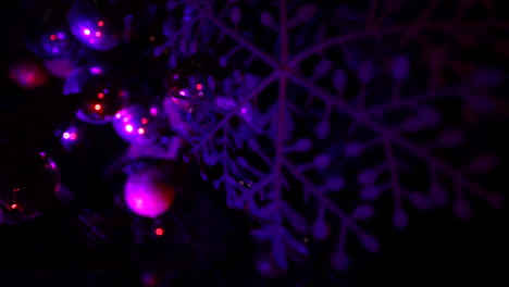 adornos de árboles de navidad en la noche con luces moradas - primer plano