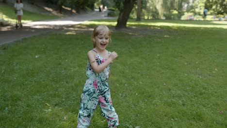 portrait of little girl smiling. child having fun in park. childhood. jumping, fighting, dancing