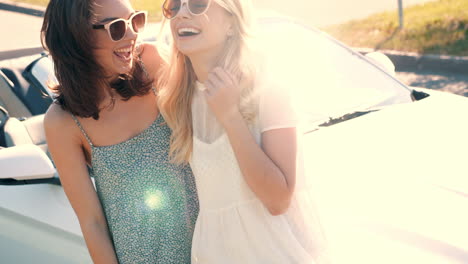 two happy friends posing next to a white convertible car