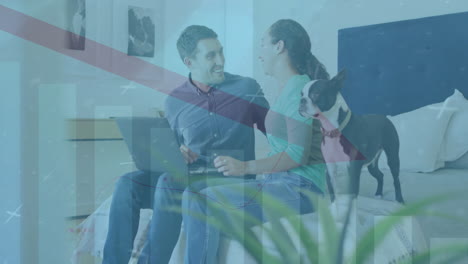 animation of arrow on falling bar graph, diverse couple with dog watching video on laptop at home