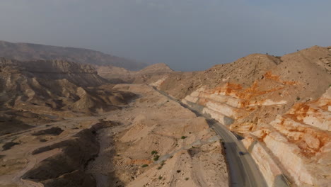 desert landscape with a coastal road winding through mountainous terrain in oman