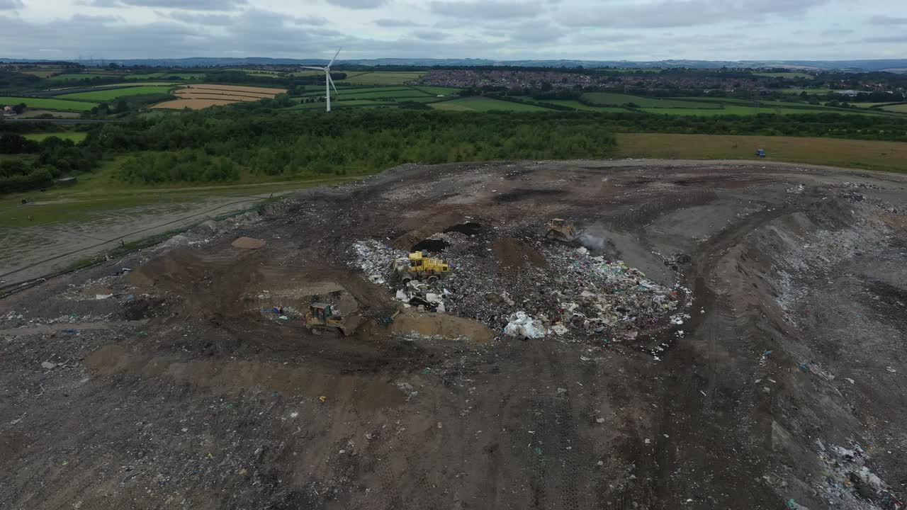 Aerial drone shot, dump trucks putting rubbish into a landfill site
