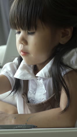 a young, asian child work and play at home learning to read and write in the cozy comfort of their living room