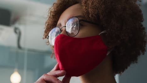 close up view of thoughtful african american woman wearing face mask with hand on chin at modern off