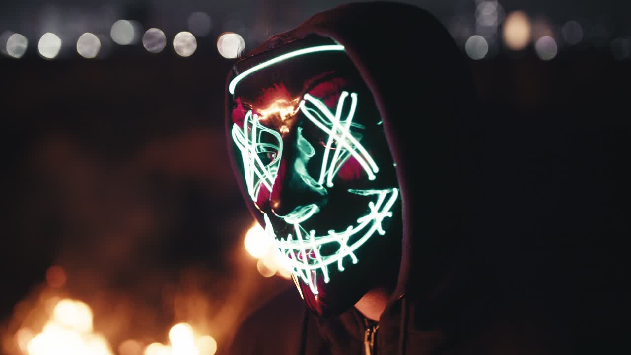 persona que usa una máscara brillante junto al pozo de fuego por la noche