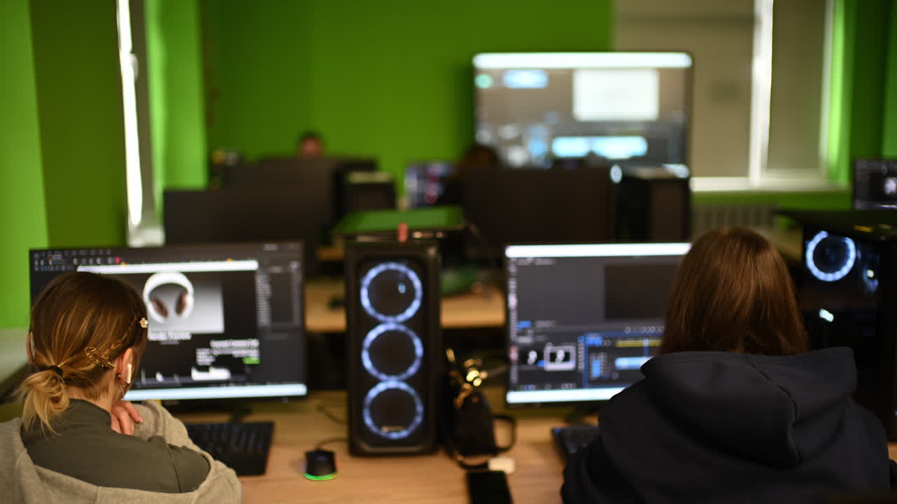 Modern computer classroom with multiple workstations, screens and students working