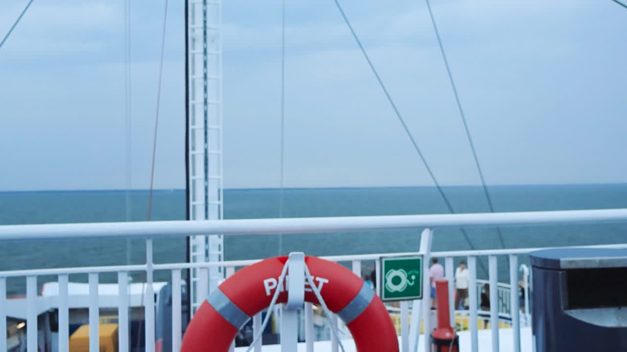 Slowly moving footage of view from the ferry deck with red lifebuoy while ferry is travelling on blue sea from route between the Estonian mainland and the island Muhu, Saaremaa in 4K during summer.
