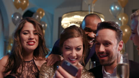 sexy friends laughing at funny viral video online watching smart phone at glamorous fashion party