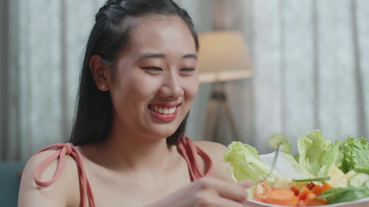 웃는 아시아 여성이 집에서 건강한 음식을 먹는 것을 즐긴다.