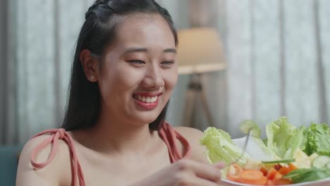 웃는 아시아 여성이 집에서 건강한 음식을 먹는 것을 즐긴다.