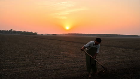 a farmer in a tilled field at sunrise
