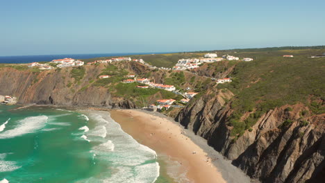 aerial: the town of arrifana with people surfing