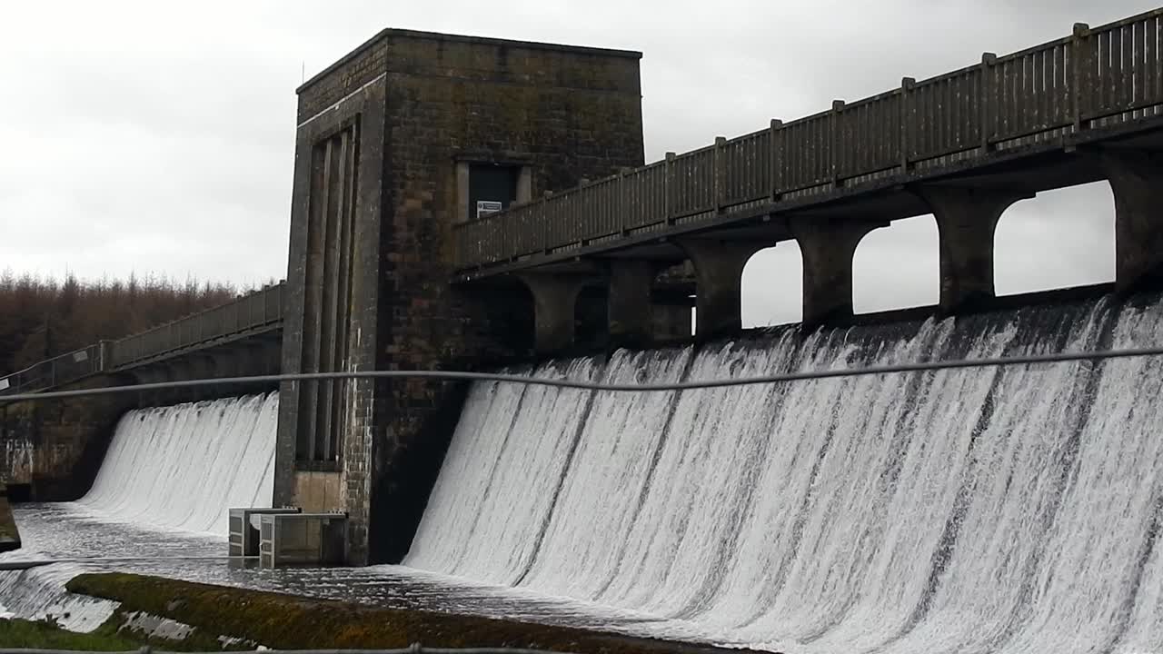 Llyn Cefni reservoir concrete dam gate pouring from Llangefni lagoon, Anglesey rural scene
