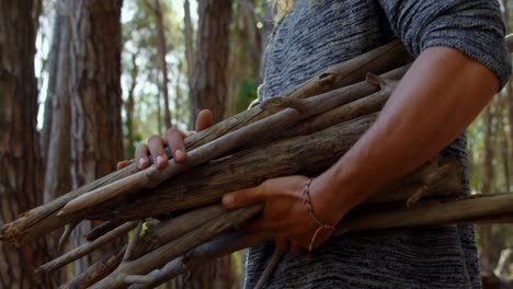 mid section of man with wooden sticks walking in the forest 4k