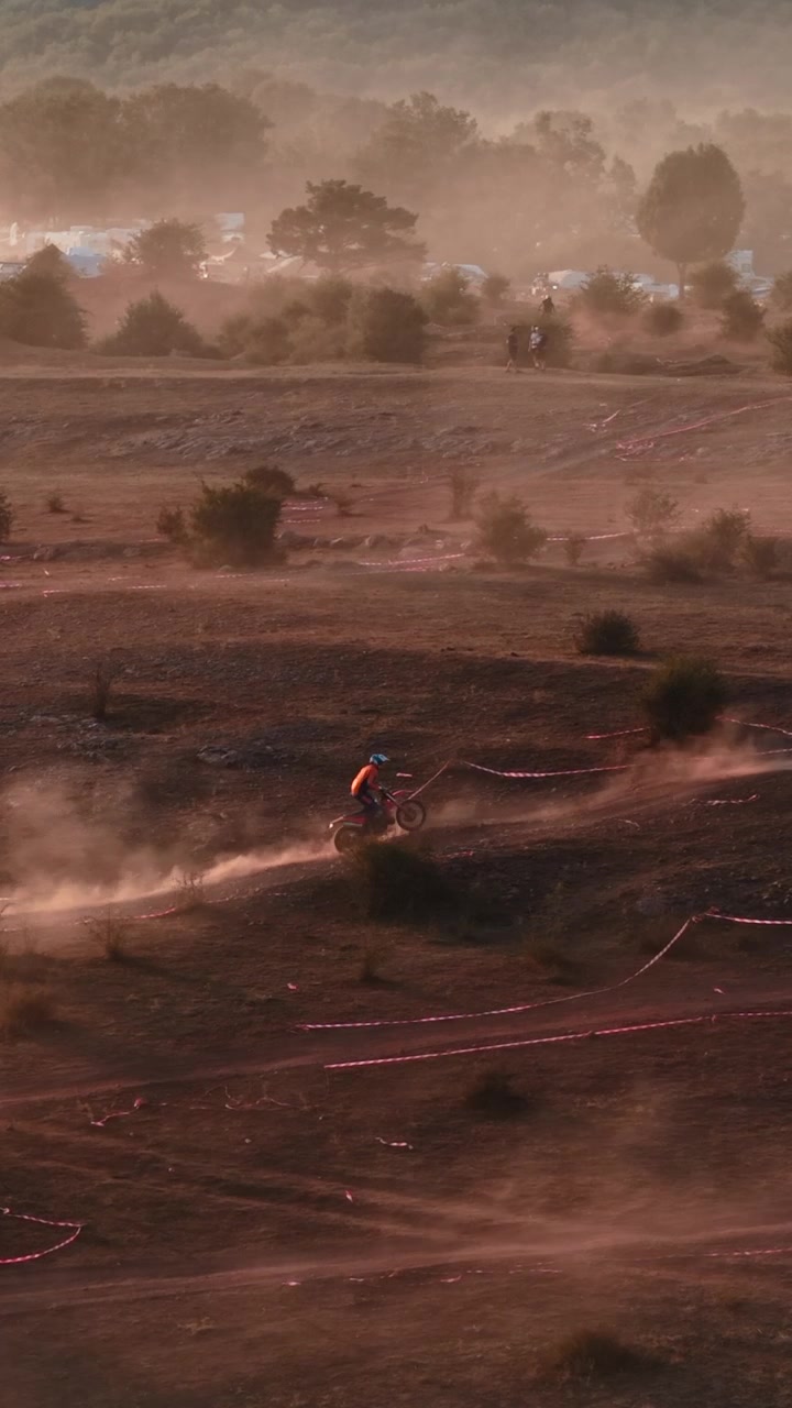 Piloti di motocross che gareggiano su una pista sterrata polverosa al tramonto
