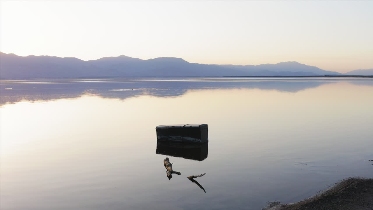 Prise de vue cinématographique du rivage salé de la mer de Salton, avec un banc en bois solitaire. Ambiance abandonnée et surréaliste dans le désert californien.