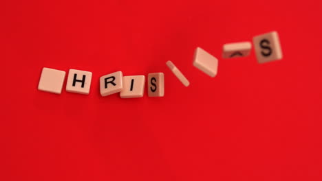 letter tiles moving to spell out christmas on red background