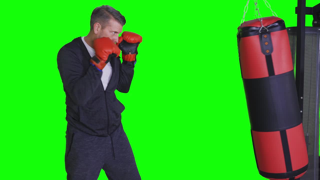 백인 남자가 스튜디오에서 권투 가방을 때리고 있다