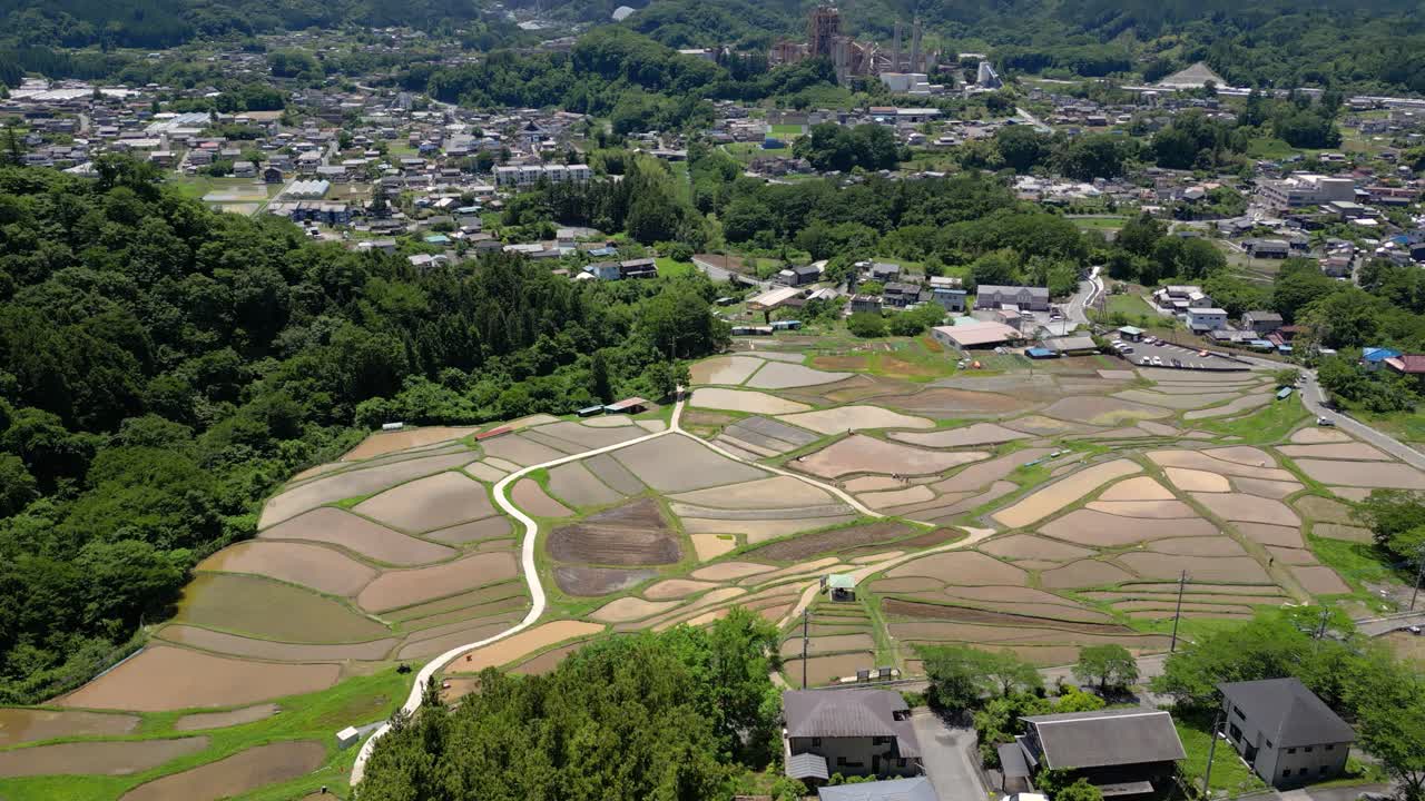 vuelo de avión no tripulado en cámara lenta inclinarse hacia arriba revelar sobre hermoso paisaje rural en japón con campos de arroz