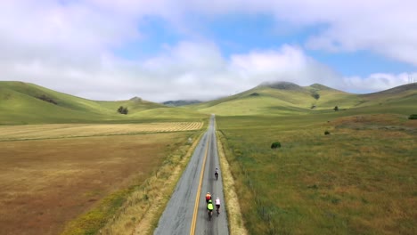 scenic landscape with cyclists riding on road through mountains - aerial drone shot