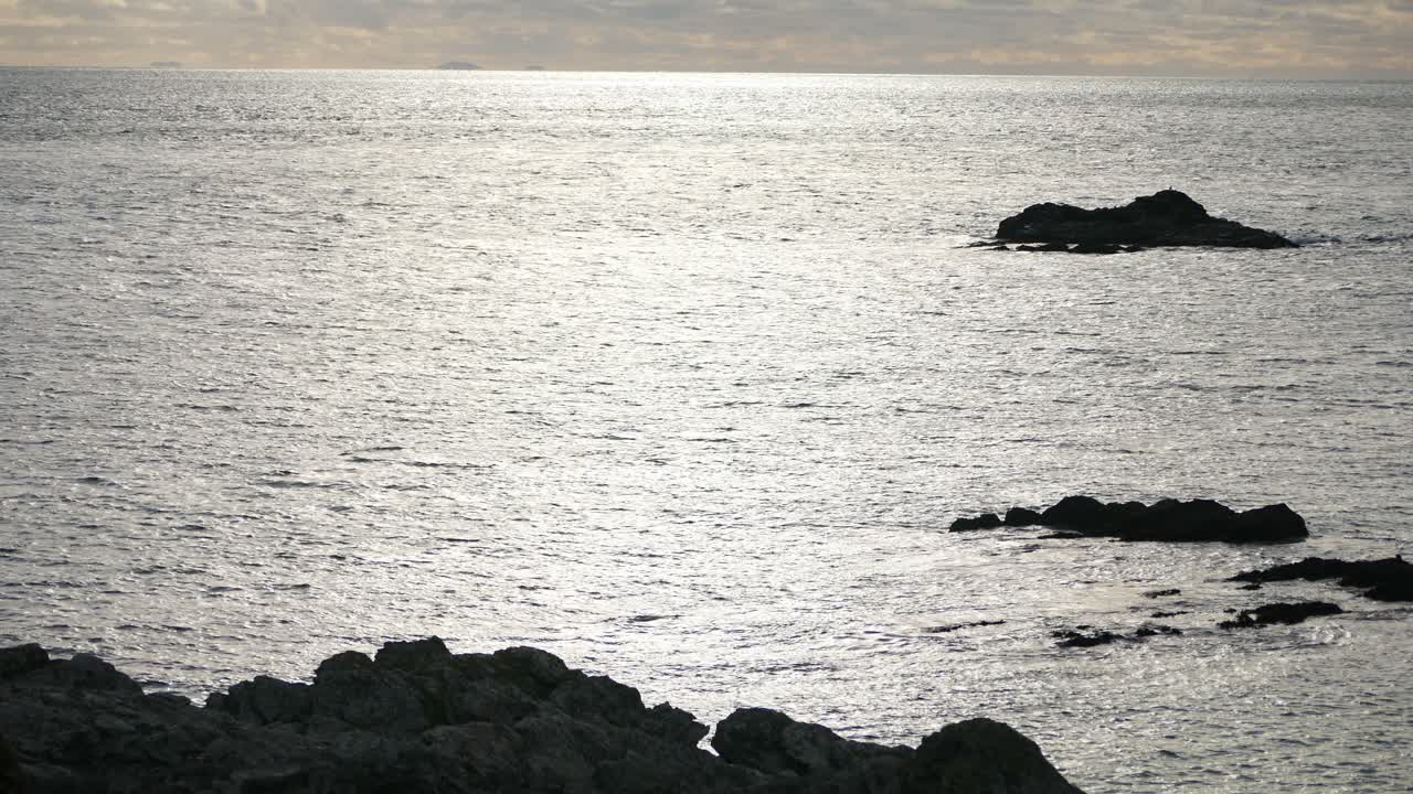 Silhouetted rocky islands in shimmering ocean coast of north wales during sunrise