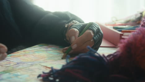 woman using a color pencil to draw a complicated sweater knitting pattern on paper. sun shining in from window. slow motion sliding shot.