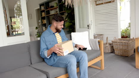 opening package, man sitting on couch and smiling in living room