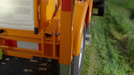 A-construction-worker-wearing-a-yellow-safety-vest-turns-a-silver-crank-on-a-mobile,-automatic-stop-sign