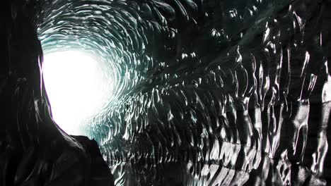 Glasmuster-Auf-Der-Eishöhlenwand-In-Island-Mit-Hellem-Licht-Am-Ende-Des-Tunnels