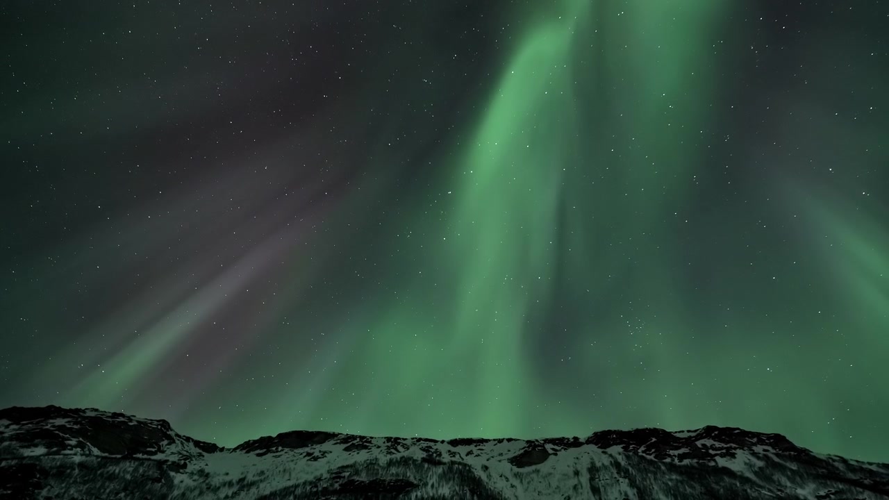 Vibrante Aurora Boreale Danzante su Vette Montuose Innevate di Notte