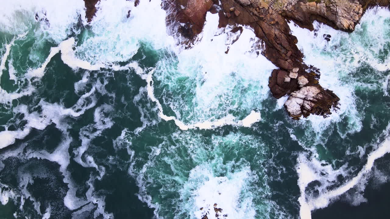 Aerea - Inquadratura dall'alto dell'oceano turbolento che si infrange contro la costa rocciosa, Hermanus, Sudafrica