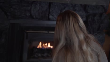 blonde woman sat looking into fireplace