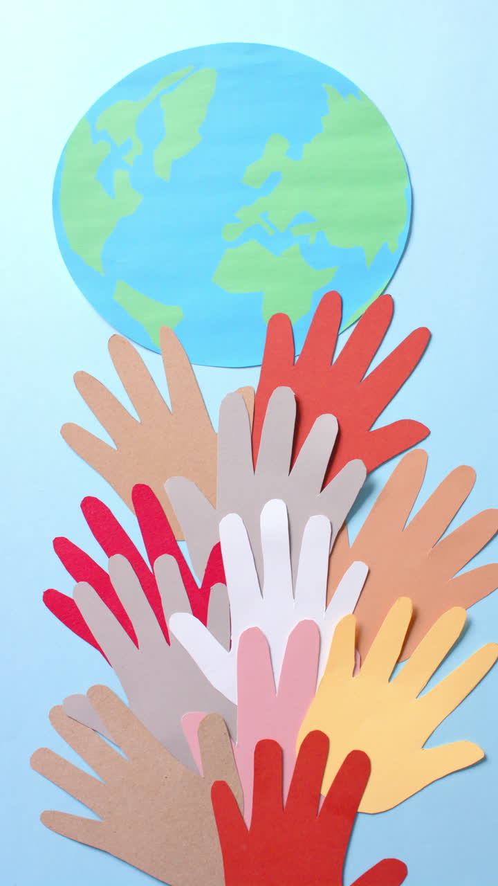 Vertical video of hands with globe made of colourful paper on white background with copy space
