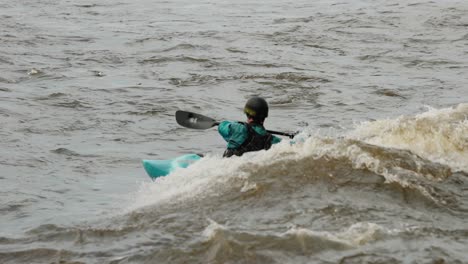 Kayakista-Vestido-De-Azul-Y-Negro-Surfea-El-Oleaje-De-Una-Ola-En-El-Río-Ottawa-Que-Fue-Creado-Por-Los-Rápidos-Durante-La-Temporada-De-Inundaciones