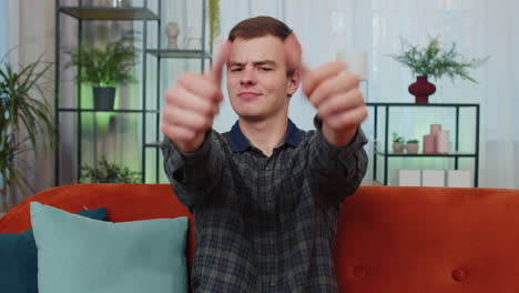 happy young man looking approvingly at camera showing thumbs up, like positive sign, good news