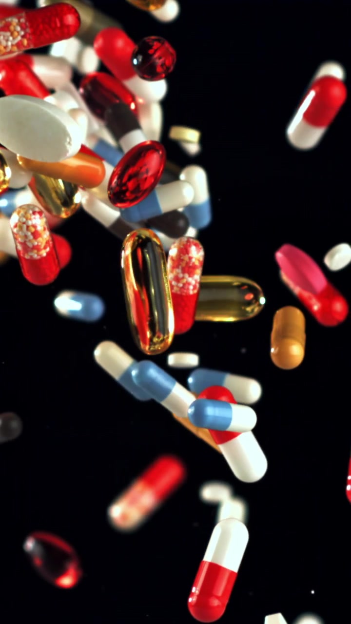 Colorful Pills and Capsules Falling in Slow Motion Against a Black Background
