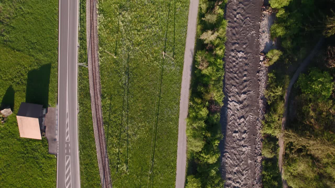 공중 드론 영상은 스위스 알프스의 그린델발트에 가까운 도로, 철도 및 강의 하향식 전망을 제공합니다.