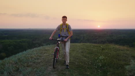 A-Tired-Teenager-With-A-Biker-Behind-His-Back-Drives-His-Bicycle-Along-The-Rural-Road-Steadicam-Shot