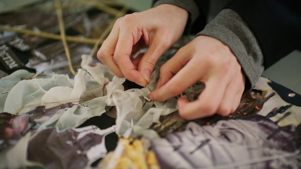 Primo piano di una tavola di design di moda concettuale coperta con materiali stratificati, tra cui corda, texture di plastica traslucida, campioni di tessuto scultoreo bianco.