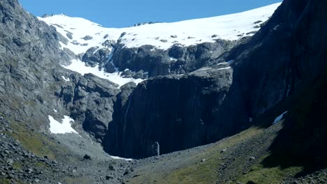 Espectáculo-Dramático-De-Agua-Cayendo-En-Cascada-Por-Un-Acantilado-Cubierto-De-Nieve,-Mostrando-La-Poderosa-Armonía-De-La-Nieve-Y-Los-Arroyos.