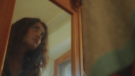 joven pensativa mirando su reflejo en un espejo de madera