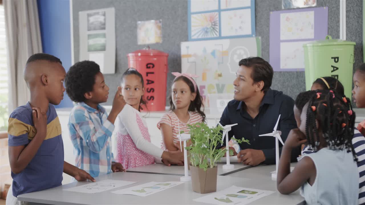 maestro masculino diverso y niños con turbinas eólicas en la clase de ecología de la escuela primaria, cámara lenta