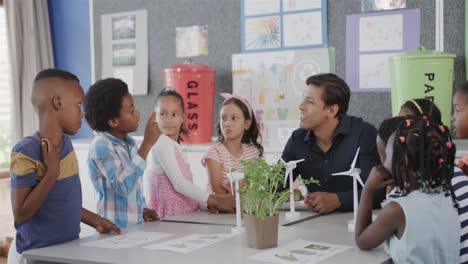 Diverse-male-teacher-and-children-with-wind-turbines-in-elementary-school-ecology-class,-slow-motion